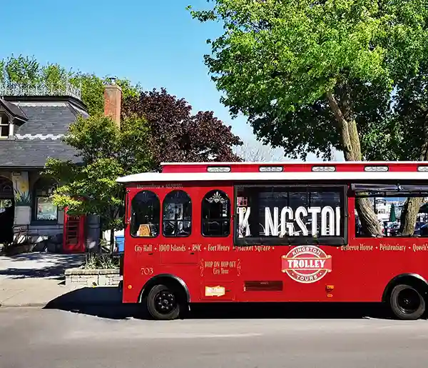 Red trolley bus framing the Kingston Sign