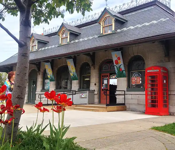Old fashioned limestone train station with a red phone booth outside the front of the building.
